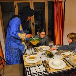 Journeys & Zen Morocco - Camp owner and host Salem Bahba serves dinner to guests at Arawan Luxury Desert Camp--personal hospitality and authentic Moroccan flavors .