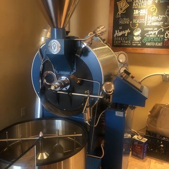 Pour Richard's Distillery - Coffee roasting machine - A coffee roasting machine featuring a large metal drum, a funnel-shaped hopper on top, and control panels on the side, situated in a coffee shop setting. - Cafes Near Me - Devon, Pennsylvania