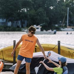 Capital Sup - Quiet Waters - Handing customer a paddle for kayak.