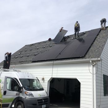 Ipsun Solar - Multiple workers are installing solar panels on the roof of a white house, with a solar installation vehicle parked nearby. - Solar Installation Near Me - Fairfax, Virginia