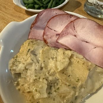 The Cornerstone - Ham and scallop potato special - A meal featuring sliced ham, scalloped potatoes with herbs, and a side of green beans, served on a white plate at a restaurant. - Bakeries Near Me - Sherman, New York