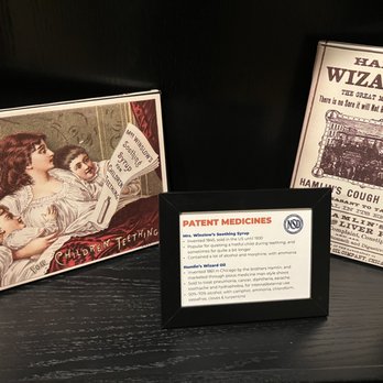 North Shore Distillery - Museum articles - Three vintage-style medicine display cards are arranged on a dark surface, including one about Mrs. Winslow's Soothing Syrup, one about Hamlin's Wizard Oil, and a small informational card. - Distilleries Near Me - Green Oaks, Illinois