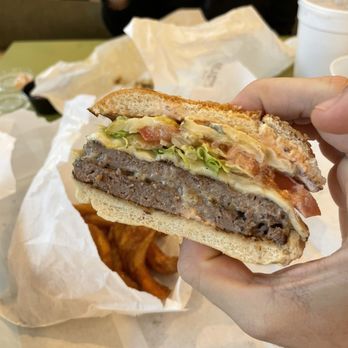 Underbelly Burger - a hand holding a sandwich - Burgers Near Me - Houston, Texas