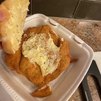 Cluck U Chicken - a hand holding a piece of breaded chicken - Chicken Wings Near Me - Toms River, New Jersey