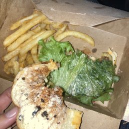 a hand holding a sandwich and french fries