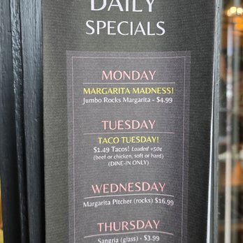 Fiesta Jalapenos - A vertical sign features daily specials for a restaurant, listing specific menu items for each day from Monday to Sunday. The sign includes margarita, taco, margarita pitcher, sangria, and kid's meal specials, with prices and additional details. The sign is placed outdoors, with a dark background and colorful text highlighting the specials. - Mexican Near Me - Ankeny, Iowa