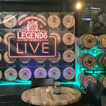 Legends Distillery - a table and chairs in front of barrels - Distilleries Near Me - Cumming, Georgia