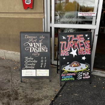 Trader Joe's - Two chalkboard signs are placed outside a store entrance, one promoting wine tasting hours and the other advertising turkey products with prices. - Grocery Near Me - Albuquerque, New Mexico