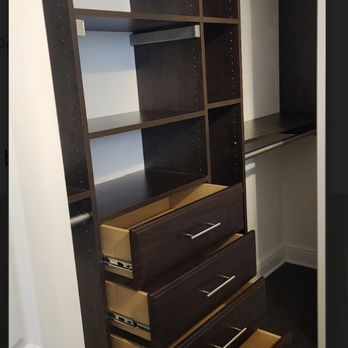 EasyClosets - A closet storage system with dark wood finish features open shelves and four drawers, some of which are partially pulled out. - Cabinetry Near Me - Parsippany, New Jersey