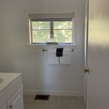 Grayhaven Motel - A bathroom features a window with a view of trees, a towel rack with towels, and a white vanity with a sink. - Hotels Near Me - Ithaca, New York
