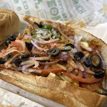 Subway - A toasted sub sandwich filled with sliced tomatoes, onions, shredded lettuce, and black olives, served on a paper-lined tray. - Sandwiches Near Me - Peekskill, New York