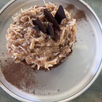 Severo - German chocolate cake - A dessert featuring shredded topping and dark chocolate pieces on a white plate, with cocoa powder and cinnamon nearby. - American Near Me - Richfield, Utah
