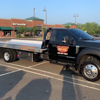 MPA Towing & Recovery - A black flatbed tow truck with "MPA Towing Recovery" branding is parked in a shopping plaza parking lot on a sunny day. - Towing Near Me - Bordentown, New Jersey MPA Towing & Recovery - A black flatbed tow truck with "MPA Towing Recovery" branding is parked in a shopping plaza parking lot on a sunny day. - Towing Near Me - Bordentown, New Jersey