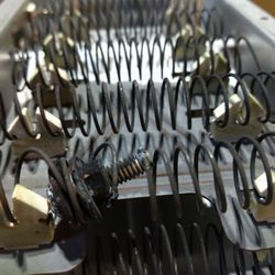 Appliance Liquidator - Heating element of a clothes dryer botched repair with a screw connecting the coils to complete the circuit.