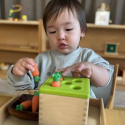 Little Explorers Montessori - Infant exploring object permanence material, developing focus, hand-eye coordination, and early cognitive skills.