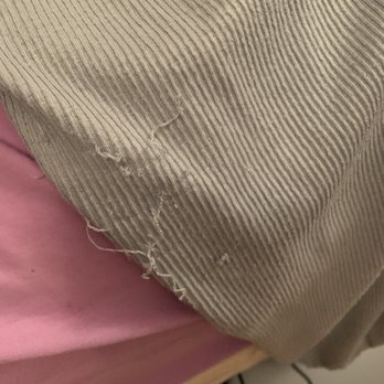 Threads - Close-up of a beige corduroy fabric with a tear and frayed edges, resting on a pink surface. - Women's Clothing Near Me - Westwood, New Jersey