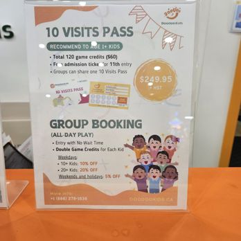 Doodoo Kids - The sign promotes Doodoo Kids, featuring a 10 visits pass priced at $249.95 plus tax, and details about group booking discounts for children, including weekday and weekend offers. The sign includes colorful illustrations of children and the Doodoo Kids logo, with contact information and website. It is placed on an orange surface, with a background showing part of a wall and some notices. - Indoor Playcenter Near Me - Markham, Ontario