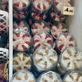 Chicka Loca - A collection of clear plastic containers filled with strawberry and caramel desserts are arranged in a freezer. The containers have transparent lids, showing the swirled whipped cream and fruit toppings inside. A small price tag indicates the cost as $4.50. The containers are stacked in an organized manner, with some on top of others, and the background includes part of the freezer interior and a white basket on the side. - Peruvian Near Me - Fairfax, Virginia