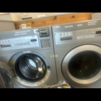 Royal Laundry - The manager is a racist - Two front-loading washing machines are shown in a laundromat, with a wooden shelf above them and some laundry items at the bottom. - Laundry Services Near Me - Indianapolis, Indiana