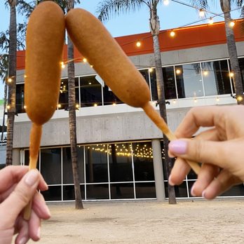 Wienerschnitzel - a person holding a hot dog on a stick - Fast Food Near Me - Mesquite, Texas