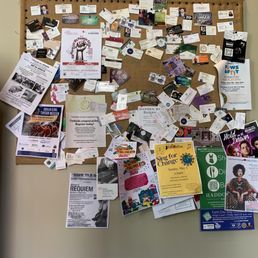 Community board! - A large cork bulletin board displays numerous flyers, posters, and notices for community events, performances, and informational announcements.