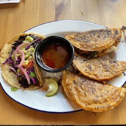 Vegan Hibiscus Taco - A plate with three grilled tacos, a small bowl of salsa, and a lime wedge, served on a wooden table.