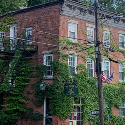 A three-story brick building with ivy growing on its facade, featuring multiple windows, a staircase, and a sign for a bed and breakfast.