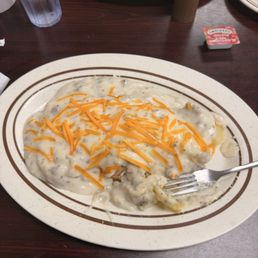Dundee Skillet - A serving of chicken and biscuits with gravy, topped with shredded cheddar cheese, on a white plate with brown stripes at a diner.