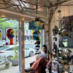 Casa Bizarro - Owner, Carrie, sitting in the display window.  Stained glass by Laura Lutton.
