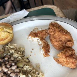 Three fried boneless tenders advertised as fried chicken breasts, wild rice, black eyed peas, and cornbread muffin. Three fried boneless tenders advertised as fried chicken breasts, wild rice, black eyed peas, and cornbread muffin.
