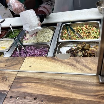 Lefalafel - a person preparing food at a buffet - Falafel Near Me - Montreal, Quebec Lefalafel - a person preparing food at a buffet - Falafel Near Me - Montreal, Quebec