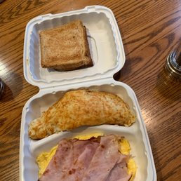 Breakfast plate with scrambled eggs, ham, potatoes, and toast