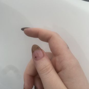 Nails Uncorked Amazon - A hand with manicured nails featuring star designs is held against a plain, light-colored surface. - Nail Salons Near Me - Eugene, Oregon
