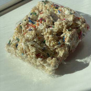 Pink Pony Soft Serve - Rice krispy treat - A clear plastic bag filled with popcorn topped with multicolored sprinkles, placed on a white surface near a window. - Ice Cream & Frozen Yogurt Near Me - Albuquerque, New Mexico