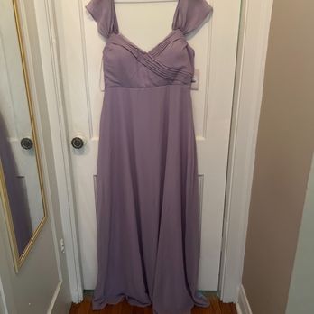 Nura Express Tailor - Original dress - A lavender-colored formal dress with cap sleeves and pleated bodice details hangs on a wooden hanger in front of a white door. - Sewing & Alterations Near Me - Chicago, Illinois