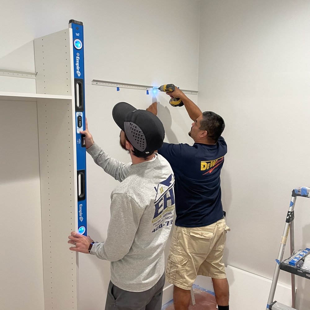 EHR - two men working on a shelf in a room - Flooring Near Me