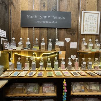 Eleganic - A soap display with bottles and bars arranged on shelves, featuring signs and decorative lighting in a store setting. - Cosmetics & Beauty Supply Near Me - St. Augustine, Florida