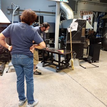 Seattle Glassblowing Studio & Gallery - Instructor rolls the glass to compress it, then heats it more - Art Galleries Near Me - Seattle, Washington Seattle Glassblowing Studio & Gallery - Instructor rolls the glass to compress it, then heats it more - Art Galleries Near Me - Seattle, Washington