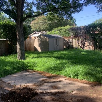 Barboza Lawns - a yard with a fence and a shed in the background - Lawn Services Near Me