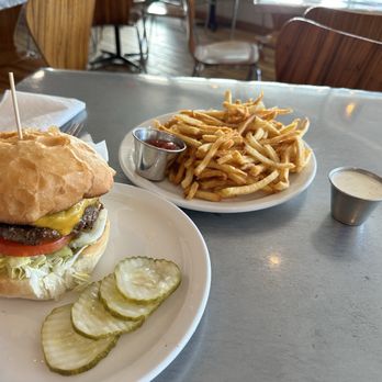 Holy Burgers - Green Chile Cheeseburgerand Hand Cut Fries - A cheeseburger with lettuce, tomato, cheese, and a beef patty on a bun, served with French fries and dipping sauces in a casual restaurant setting. - Burgers Near Me - Albuquerque, New Mexico