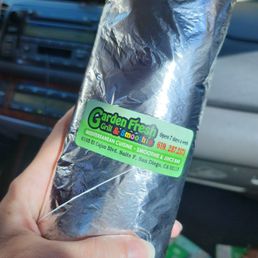 a person holding a sandwich wrapped in aluminum foil a person holding a sandwich wrapped in aluminum foil