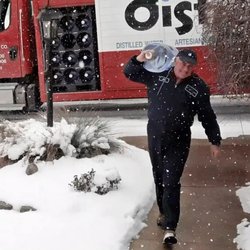 Distillata - Distillata Water delivery driver carrying a 5-gallon water bottle from truck