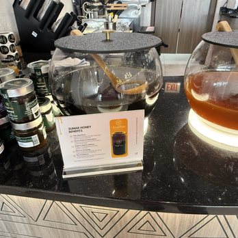 Asal Bee Cafe - Display of two glass honey dispensers with a sign explaining the benefits of Sumar Honey at Asal Bee Cafe. - Coffee & Tea Near Me - Bridgeview, Illinois