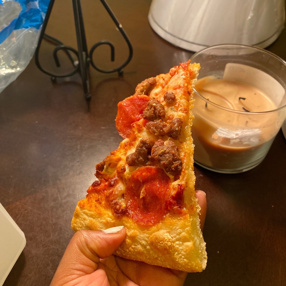 a hand holding a slice of pizza a hand holding a slice of pizza