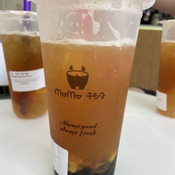 MoMo Tea - A bubble tea beverage in a clear plastic cup with a straw, containing tapioca pearls at the bottom and a light brown liquid. - Bubble Tea Near Me - Bellmore, New York