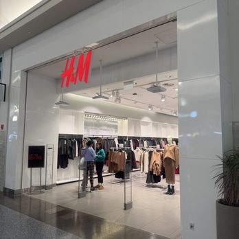 H&M-Paramus - An H&M retail store in a shopping mall features clothing racks and a mannequin, with customers browsing inside. - Women's Clothing Near Me - Paramus, New Jersey
