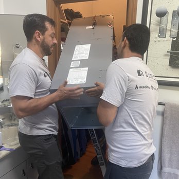 SumZero Energy Systems - Lifting air handler to attic - Two technicians are handling a large HVAC component in a doorway, with tools and equipment visible nearby. - Heating & Air Conditioning/HVAC Near Me - Holliston, Massachusetts