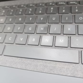 Lowe's Home Improvement - The image depicts a close-up view of a laptop keyboard with gray keys, including the letters B, N, M, and surrounding keys. The surface around the keyboard is also gray and appears to have some dust or smudges. The top part of the image shows part of the laptop's screen bezel. The photo is taken at an angle, focusing on the central keys. - Home Decor Near Me - Phoenix, Arizona