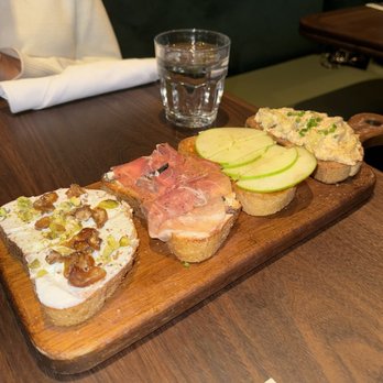 Postino Addison - Bruschetta Board, left to right: (1) RICOTTA, DATES & PISTACHIO (2) PROSCIUTTO, FIG & MASCARPONE, (3) BRIE, APPLE & FIG, (4) WARM ARTICHOKE - Wine Bars Near Me - Dallas, Texas Postino Addison - Bruschetta Board, left to right: (1) RICOTTA, DATES & PISTACHIO (2) PROSCIUTTO, FIG & MASCARPONE, (3) BRIE, APPLE & FIG, (4) WARM ARTICHOKE - Wine Bars Near Me - Dallas, Texas