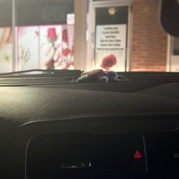 Closed way before 6:30 - A plush toy is positioned on the dashboard of a car, with a storefront visible in the background through the windshield at night.